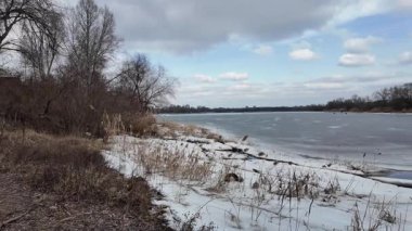 Donmuş göl üzerindeki ağır çekim kış manzarası. Nehirde buzlar kırıldı. Vahşi doğada kuş gözlemciliği. 4K 'de ağır çekim videosu. Göl kıyısının soğuk kış soğuğunun elde tutulan videosu.