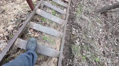 Bir adamın, evdeki doğal ahşap bir merdivenden inişine bakış açısı. Ev turu konseptine ilk kişi bakış açısı. Eski tehlikeli merdivenler.