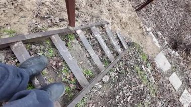 Bir adamın, evdeki doğal ahşap bir merdivenden inişine bakış açısı. Ev turu konseptine ilk kişi bakış açısı. Eski tehlikeli merdivenler.