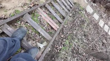 Bir adamın, evdeki doğal ahşap bir merdivenden inişine bakış açısı. Ev turu konseptine ilk kişi bakış açısı. Eski tehlikeli merdivenler.