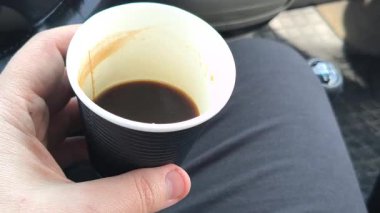 Kahve sürücünün elinde. Bir adam arabada bir fincan kahve tutar. Arabada kahve..