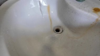 Pis lavabo. Musluktan gelen su lavaboya akıyor. Lavabodaki pas. Ağır çekim yüksek çözünürlüklü video.