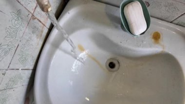 Pis lavabo. Musluktan gelen su lavaboya akıyor. Lavabodaki pas. Ağır çekim yüksek çözünürlüklü video.