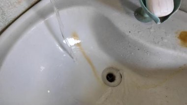 Pis lavabo. Musluktan gelen su lavaboya akıyor. Lavabodaki pas. Ağır çekim yüksek çözünürlüklü video.