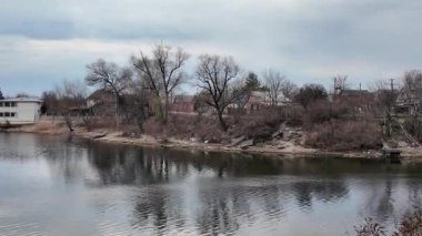 Göl kıyısındaki manzara. Nehirdeki yansıma. Nehrin kumlu kıyısı ve karanlık su. Doğa manzarası. Denize doğru yürü. Suda küçük dalgalar.