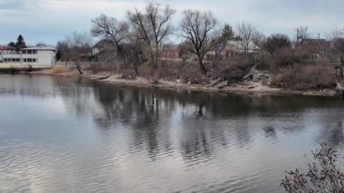 Göl kıyısındaki manzara. Nehirdeki yansıma. Nehrin kumlu kıyısı ve karanlık su. Doğa manzarası. Denize doğru yürü. Suda küçük dalgalar.