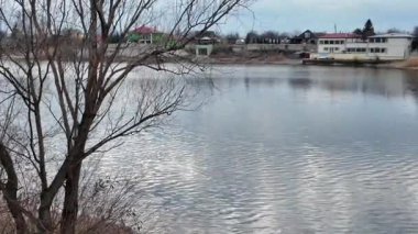 Göl kıyısındaki manzara. Nehirdeki yansıma. Nehrin kumlu kıyısı ve karanlık su. Doğa manzarası. Denize doğru yürü. Suda küçük dalgalar.