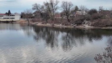 Göl kıyısındaki manzara. Nehirdeki yansıma. Nehrin kumlu kıyısı ve karanlık su. Doğa manzarası. Denize doğru yürü. Suda küçük dalgalar.