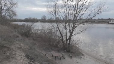 Göl kıyısındaki manzara. Nehirdeki yansıma. Nehrin kumlu kıyısı ve karanlık su. Doğa manzarası. Denize doğru yürü. Suda küçük dalgalar.