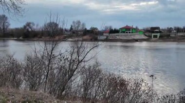 Göl kıyısındaki manzara. Nehirdeki yansıma. Nehrin kumlu kıyısı ve karanlık su. Doğa manzarası. Denize doğru yürü. Suda küçük dalgalar.