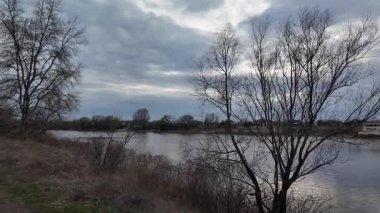 Göl kıyısındaki manzara. Nehirdeki yansıma. Nehrin kumlu kıyısı ve karanlık su. Doğa manzarası. Denize doğru yürü. Suda küçük dalgalar.