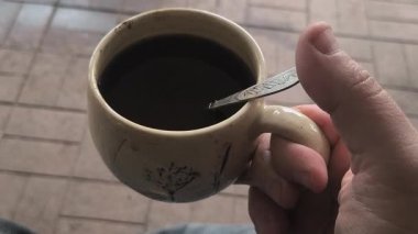Ellerinde güzel bir fincan kahve. Sıra dışı bardak. Bir fincan kil çay. Kahve içen bir adam. Çay içen adam. canlı kamera.