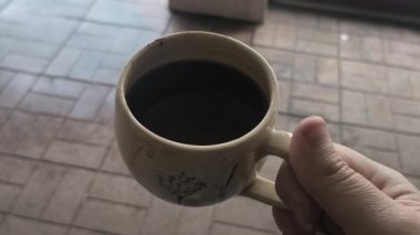 Ellerinde güzel bir fincan kahve. Sıra dışı bardak. Bir fincan kil çay. Kahve içen bir adam. Çay içen adam. canlı kamera.