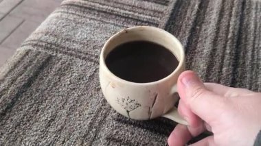 Ellerinde güzel bir fincan kahve. Sıra dışı bardak. Bir fincan kil çay. Kahve içen bir adam. Çay içen adam. canlı kamera.
