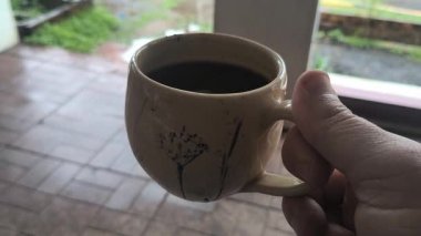 Ellerinde güzel bir fincan kahve. Sıra dışı bardak. Bir fincan kil çay. Kahve içen bir adam. Çay içen adam. canlı kamera.
