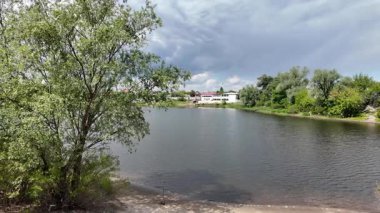 Nehir ve kasvetli gökyüzü manzarası. Yavaş çekim video doğa manzarası. Yağmurdan önce hava durumu. Fırtınadan önce gökyüzü. Güneş ve yoğun yağmur bulutları. Nehir ve kumlu sahil. Nehirde karanlık su.