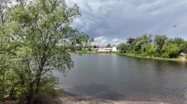 Nehir ve kasvetli gökyüzü manzarası. Yavaş çekim video doğa manzarası. Yağmurdan önce hava durumu. Fırtınadan önce gökyüzü. Güneş ve yoğun yağmur bulutları. Nehir ve kumlu sahil. Nehirde karanlık su.