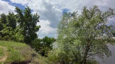 Nehir ve kasvetli gökyüzü manzarası. Yavaş çekim video doğa manzarası. Yağmurdan önce hava durumu. Fırtınadan önce gökyüzü. Güneş ve yoğun yağmur bulutları. Nehir ve kumlu sahil. Nehirde karanlık su.