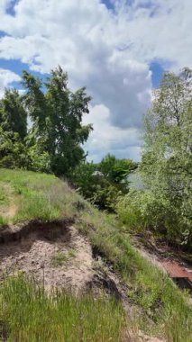 Nehir ve kasvetli gökyüzü manzarası. Yavaş çekim video doğa manzarası. Yağmurdan önce hava durumu. Fırtınadan önce gökyüzü. Güneş ve yoğun yağmur bulutları. Nehir ve kumlu sahil. Nehirde karanlık su.