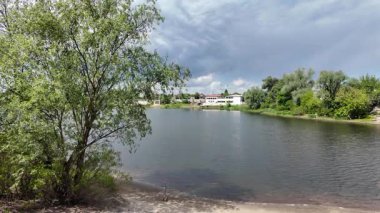 Nehir ve kasvetli gökyüzü manzarası. Yavaş çekim video doğa manzarası. Yağmurdan önce hava durumu. Fırtınadan önce gökyüzü. Güneş ve yoğun yağmur bulutları. Nehir ve kumlu sahil. Nehirde karanlık su.