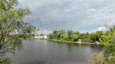 Nehir ve kasvetli gökyüzü manzarası. Yavaş çekim video doğa manzarası. Yağmurdan önce hava durumu. Fırtınadan önce gökyüzü. Güneş ve yoğun yağmur bulutları. Nehir ve kumlu sahil. Nehirde karanlık su.