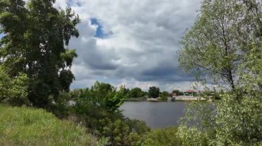 Nehir ve kasvetli gökyüzü manzarası. Yavaş çekim video doğa manzarası. Yağmurdan önce hava durumu. Fırtınadan önce gökyüzü. Güneş ve yoğun yağmur bulutları. Nehir ve kumlu sahil. Nehirde karanlık su.