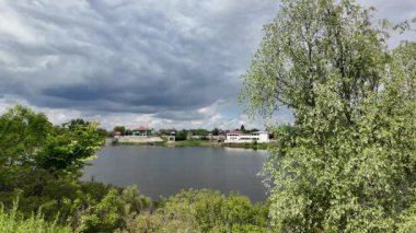 Nehir ve kasvetli gökyüzü manzarası. Yavaş çekim video doğa manzarası. Yağmurdan önce hava durumu. Fırtınadan önce gökyüzü. Güneş ve yoğun yağmur bulutları. Nehir ve kumlu sahil. Nehirde karanlık su.