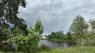 Nehir ve kasvetli gökyüzü manzarası. Yavaş çekim video doğa manzarası. Yağmurdan önce hava durumu. Fırtınadan önce gökyüzü. Güneş ve yoğun yağmur bulutları. Nehir ve kumlu sahil. Nehirde karanlık su.