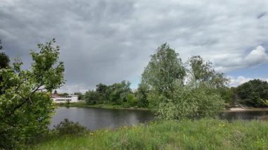 Nehir ve kasvetli gökyüzü manzarası. Yavaş çekim video doğa manzarası. Yağmurdan önce hava durumu. Fırtınadan önce gökyüzü. Güneş ve yoğun yağmur bulutları. Nehir ve kumlu sahil. Nehirde karanlık su.