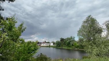 Nehir ve kasvetli gökyüzü manzarası. Yavaş çekim video doğa manzarası. Yağmurdan önce hava durumu. Fırtınadan önce gökyüzü. Güneş ve yoğun yağmur bulutları. Nehir ve kumlu sahil. Nehirde karanlık su.