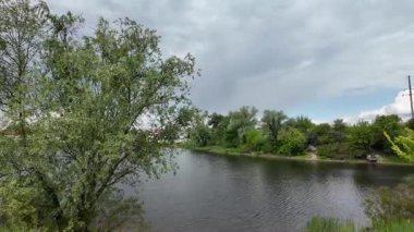 Nehir ve kasvetli gökyüzü manzarası. Yavaş çekim video doğa manzarası. Yağmurdan önce hava durumu. Fırtınadan önce gökyüzü. Güneş ve yoğun yağmur bulutları. Nehir ve kumlu sahil. Nehirde karanlık su.