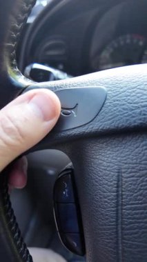 Şoför kornaya basar. Şoför araba sürerken korna çalar. Şoför direksiyonu tutuyor..