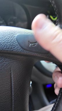 Şoför kornaya basar. Şoför araba sürerken korna çalar. Şoför direksiyonu tutuyor..