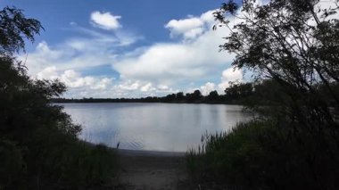 Bulutlar suda yansıyor. Gökyüzü ve nehir. Göllü doğal manzara. Göl üzerinde yağmur bulutları. Nehirdeki pürüzsüz karanlık su. Yavaş çekim video doğal manzara. doğa arkaplanı.