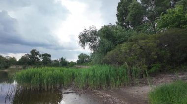 Bulutlar suda yansıyor. Gökyüzü ve nehir. Göllü doğal manzara. Göl üzerinde yağmur bulutları. Nehirdeki pürüzsüz karanlık su. Yavaş çekim video doğal manzara. doğa arkaplanı.