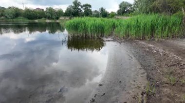 Bulutlar suda yansıyor. Gökyüzü ve nehir. Göllü doğal manzara. Göl üzerinde yağmur bulutları. Nehirdeki pürüzsüz karanlık su. Yavaş çekim video doğal manzara. doğa arkaplanı.