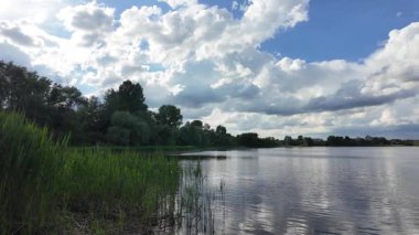 Bulutlar suda yansıyor. Gökyüzü ve nehir. Göllü doğal manzara. Göl üzerinde yağmur bulutları. Nehirdeki pürüzsüz karanlık su. Yavaş çekim video doğal manzara. doğa arkaplanı.