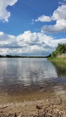Bulutlar suda yansıyor. Gökyüzü ve nehir. Göllü doğal manzara. Göl üzerinde yağmur bulutları. Nehirdeki pürüzsüz karanlık su. Yavaş çekim video doğal manzara. doğa arkaplanı.