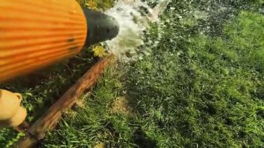 Bahçıvan bahçeyi bir hortumla sular. Yaz kuraklığı sırasında bahçe hortumuyla yeşil arka bahçe çimlerini sulamak..