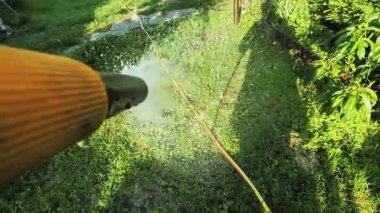 Bahçıvan bahçeyi bir hortumla sular. Yaz kuraklığı sırasında bahçe hortumuyla yeşil arka bahçe çimlerini sulamak..