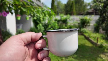Klasik metal bardak. Bir el, Endonezya 'dan yeşil ekran arka planlı geleneksel bir yeşil metal bardak tutuyor. Yavaş çekim video bardağı elinde.
