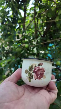 Klasik metal bardak. Bir el, Endonezya 'dan yeşil ekran arka planlı geleneksel bir yeşil metal bardak tutuyor. Yavaş çekim video bardağı elinde.