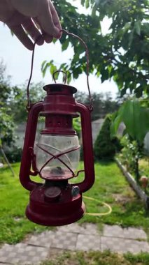 Geceleri ormandaki çimlerin üzerinde antik bir gaz lambası. Bir insan fenerinin yakın eli ışığın feneridir. Açık Kamp Konsepti. 4k video