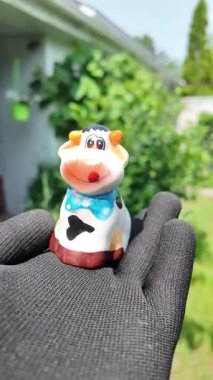 Cam oyuncak inek. Küçük oyuncak inek elinde. oyuncak inek heykelciği. Oyuncak inek çimlerin üzerinde. Çimlerin üzerinde bir inek heykeli. Salgının ekonomi üzerindeki etkisi..