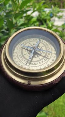 Eski pusula ellerinde. Adam yeri bulmak için pusulayı kullanıyor. Yakın çekim seyahat konsepti. Pusula bir ileri bir geri hareket ediyor. 4k video