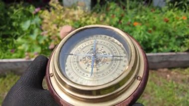Eski pusula ellerinde. Adam yeri bulmak için pusulayı kullanıyor. Yakın çekim seyahat konsepti. Pusula bir ileri bir geri hareket ediyor. 4k video