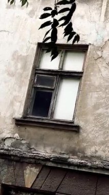 Harap olmuş bir evde eski bir pencere. Duvardaki eski kırık ahşap pencere. Çatlak bir evin duvarı. Terk edilmiş ev.