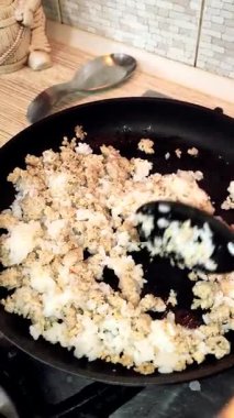 Tavada pirinç lapası. Pirinç pişiren adam. Kızartma tavasında et ve lapa. Adam ocakta yemek pişiriyor. Basit bir mutfak. evde yemek pişirmek.