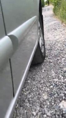 Taşradaki yağmur havuzlarının üzerinde araba lastiği sürerken çekilmiş dikey yavaş çekim videosu. Araba ormanın içinden geçiyor. Milli parktaki orman yolu..