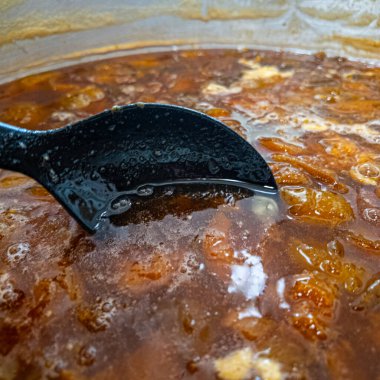 Büyük bir tencereye sıkıştır. Erik reçeli. Kayısı reçeli. Tencerede kayısı reçeli, yukarıdan görüntü. Ocaktaki tencerede kokulu portakal meyvesi ve köpük..